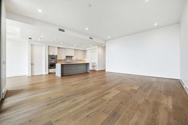 unfurnished living room with recessed lighting, baseboards, visible vents, and light wood-type flooring