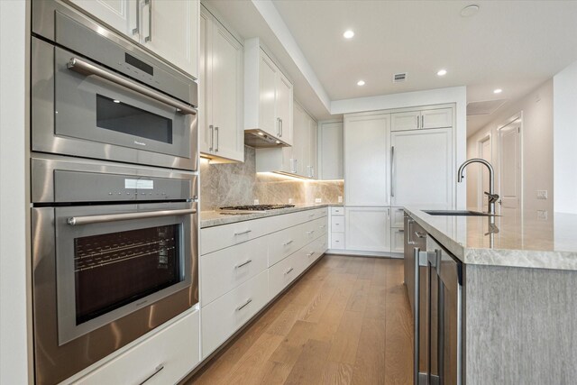 kitchen featuring visible vents, recessed lighting, white cabinets, a sink, and light wood-style flooring