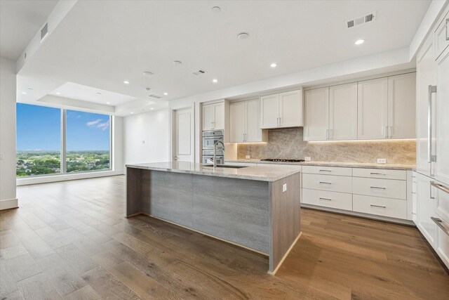 kitchen with visible vents, recessed lighting, an island with sink, and backsplash