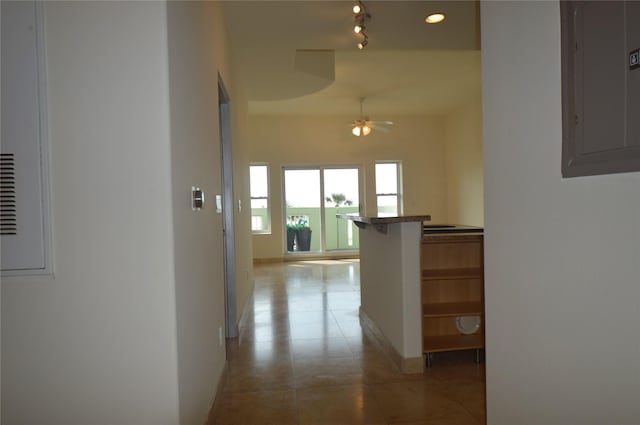 hall featuring electric panel, baseboards, and light tile patterned flooring