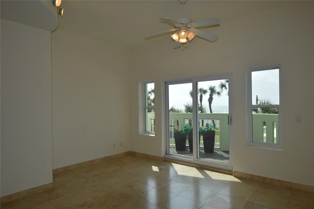 tiled empty room with plenty of natural light, baseboards, and ceiling fan