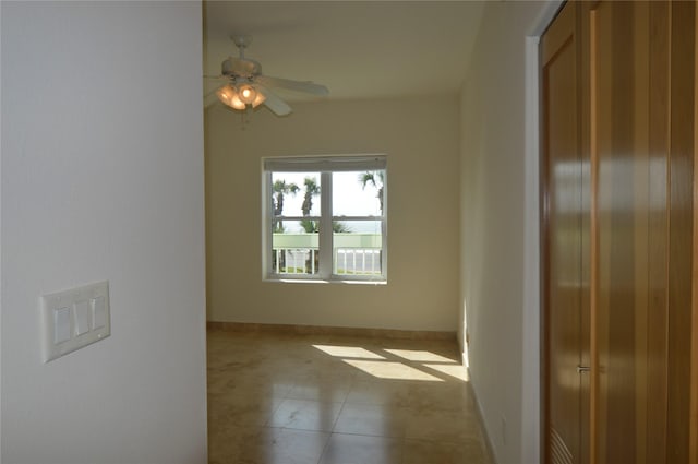 spare room featuring tile patterned floors, baseboards, and ceiling fan
