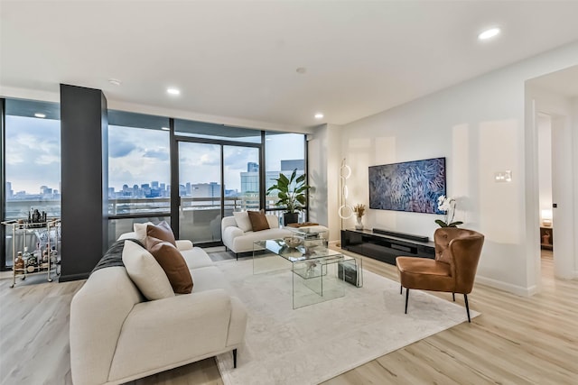 living room featuring baseboards, floor to ceiling windows, wood finished floors, and recessed lighting