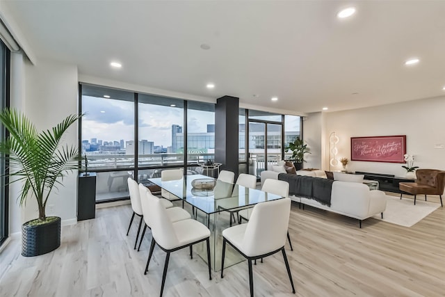 dining area with light wood-type flooring, a city view, floor to ceiling windows, and recessed lighting