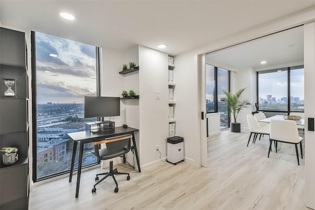office with floor to ceiling windows, light wood finished floors, baseboards, and recessed lighting