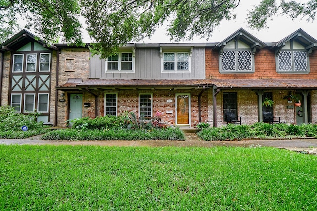 view of front facade with a front lawn, brick siding, and covered porch