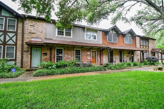 view of front of property with brick siding, a porch, a front yard, and board and batten siding