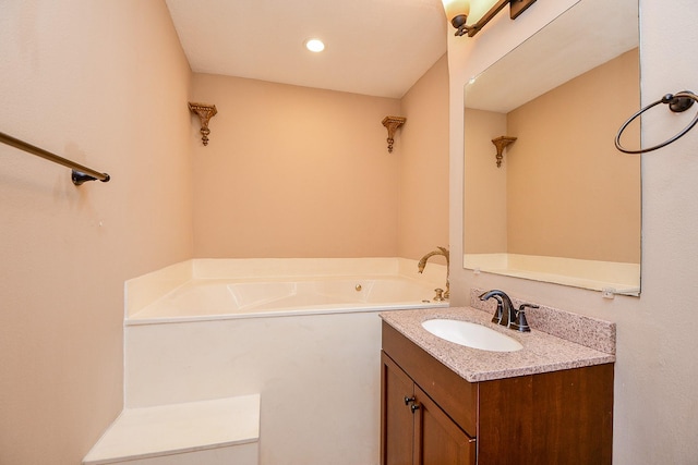 bathroom with a bath, vanity, and recessed lighting