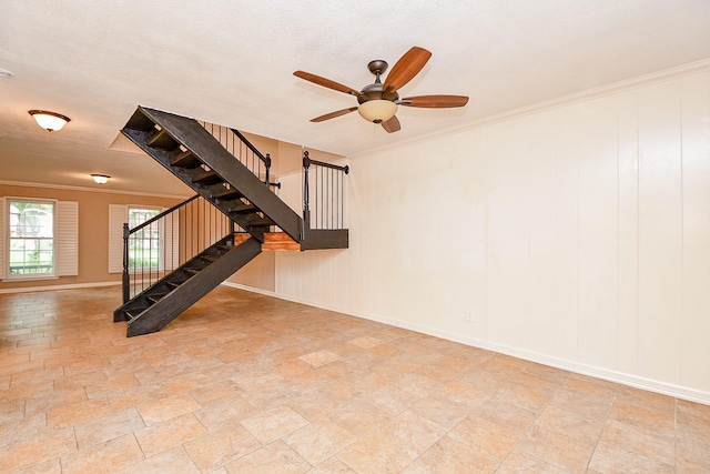 empty room with crown molding, a ceiling fan, stairs, stone finish flooring, and baseboards