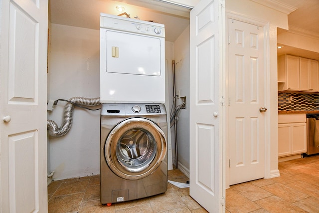 clothes washing area featuring stone finish flooring, stacked washer / dryer, ornamental molding, and laundry area