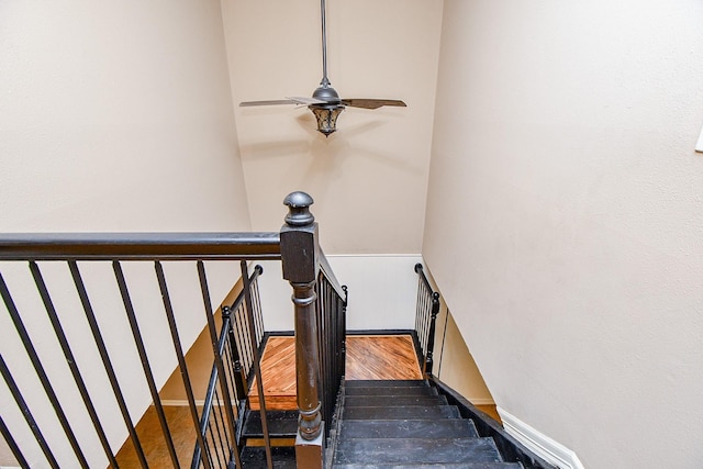 staircase with a ceiling fan and wood finished floors