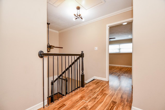 hallway featuring attic access, light wood-style flooring, baseboards, and an upstairs landing