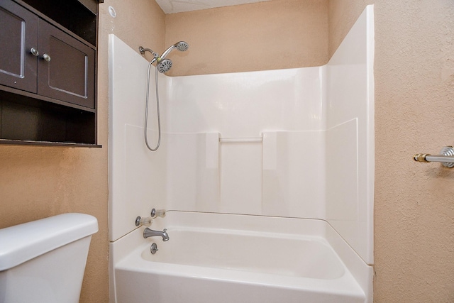 bathroom featuring a textured wall, toilet, and shower / bathtub combination