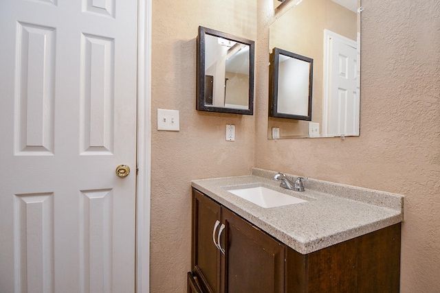 bathroom with a textured wall and vanity