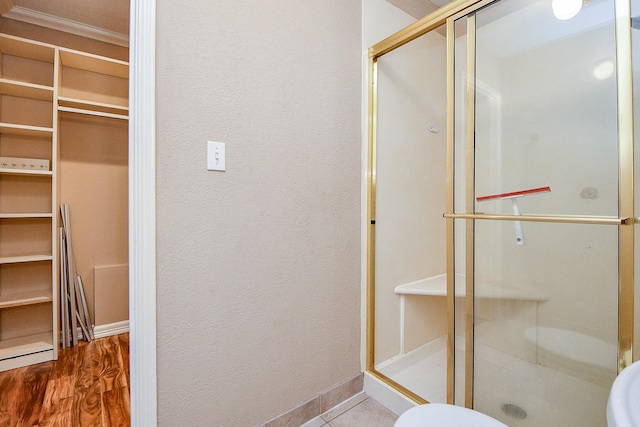 full bathroom featuring crown molding, toilet, baseboards, and a stall shower