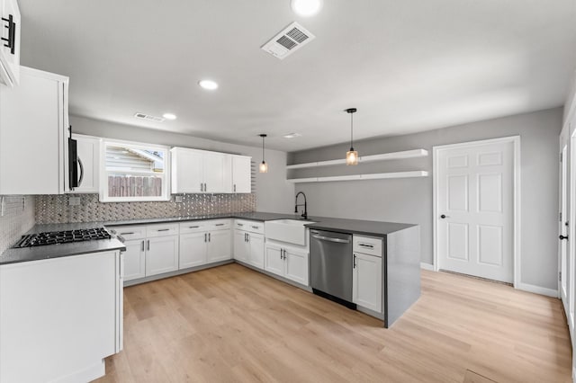kitchen featuring dark countertops, visible vents, a sink, a peninsula, and appliances with stainless steel finishes