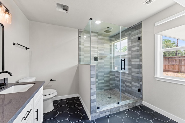 full bathroom featuring toilet, a stall shower, vanity, baseboards, and visible vents