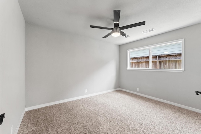 carpeted spare room featuring baseboards, a ceiling fan, and visible vents