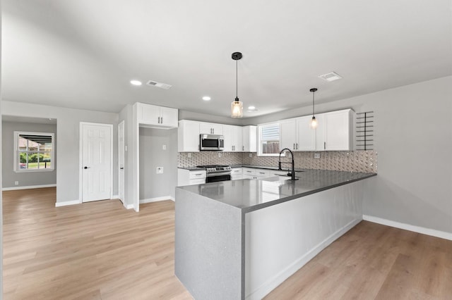 kitchen with stainless steel appliances, a peninsula, visible vents, white cabinetry, and decorative backsplash