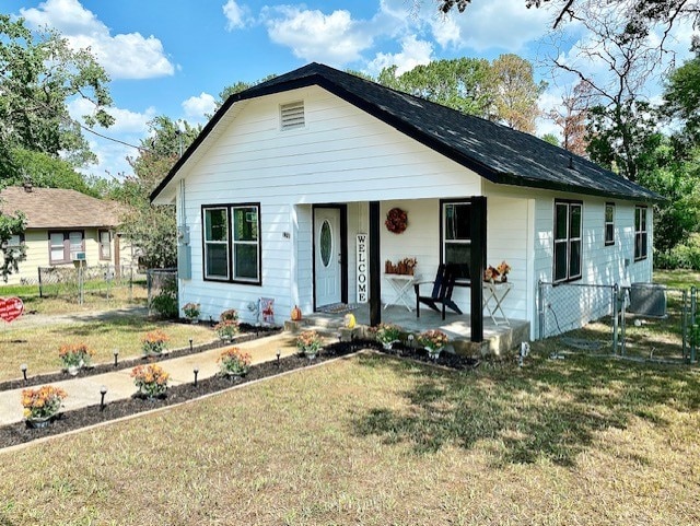 bungalow featuring a front lawn, covered porch, and fence