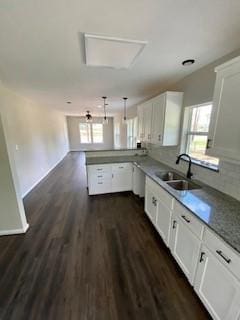 kitchen with a peninsula, white cabinetry, a sink, and plenty of natural light
