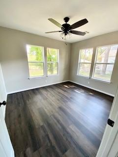 spare room with ceiling fan, baseboards, and dark wood-style flooring