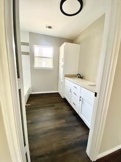 bathroom with double vanity, wood finished floors, and baseboards