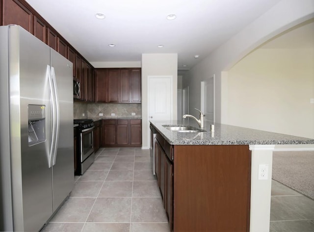 kitchen with light tile patterned flooring, light stone countertops, stainless steel appliances, and a sink