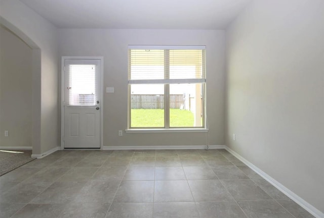 doorway featuring a wealth of natural light, tile patterned flooring, and baseboards