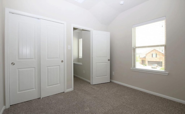 unfurnished bedroom with vaulted ceiling, carpet floors, a closet, and baseboards