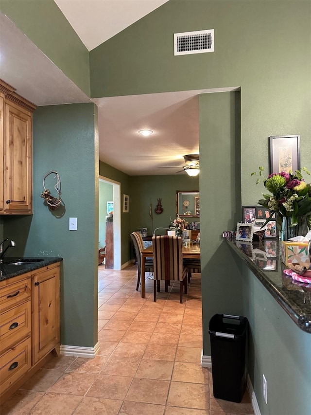 kitchen with visible vents, a ceiling fan, light tile patterned floors, a sink, and high vaulted ceiling