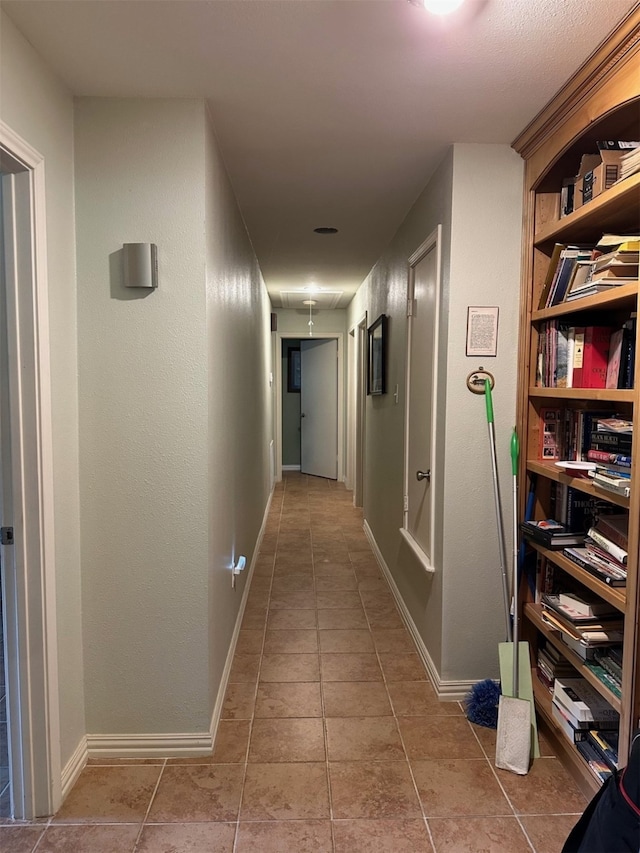 corridor with baseboards and tile patterned flooring