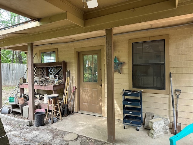 entrance to property featuring fence and a ceiling fan