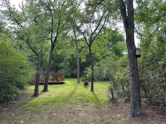 view of yard with a forest view and a deck