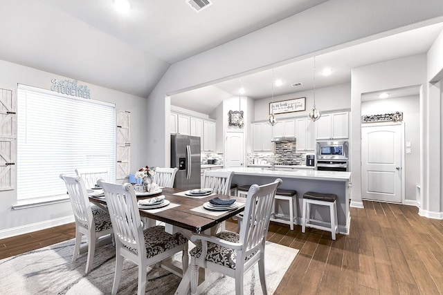 dining area with visible vents, vaulted ceiling, baseboards, and dark wood finished floors
