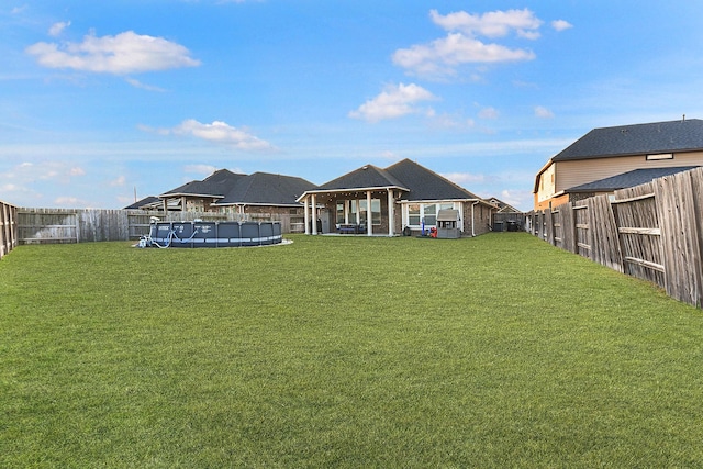 rear view of house with a fenced backyard, a gazebo, a fenced in pool, and a lawn