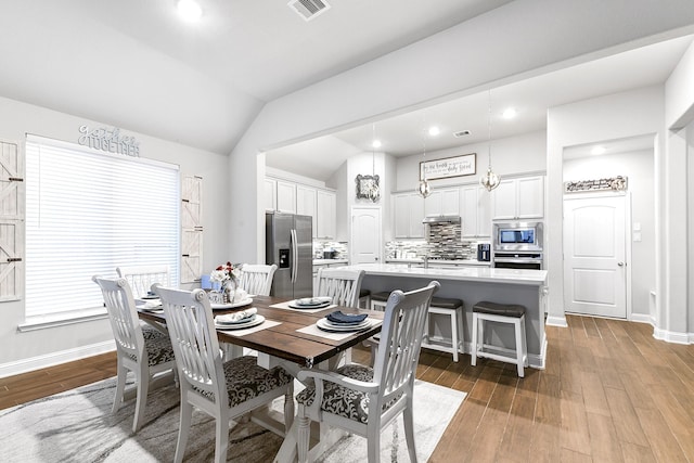 dining space with vaulted ceiling, baseboards, wood finished floors, and visible vents