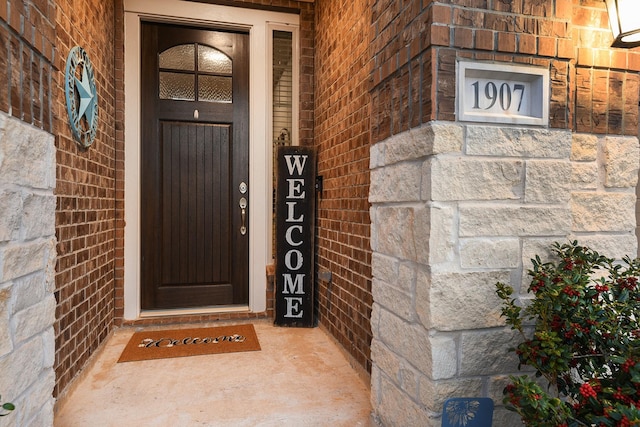 doorway to property with brick siding and stone siding