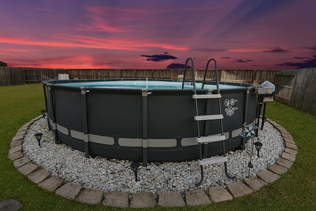 view of swimming pool with a lawn, a fenced in pool, and a fenced backyard