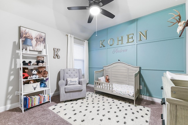 carpeted bedroom featuring a crib, vaulted ceiling, baseboards, and ceiling fan
