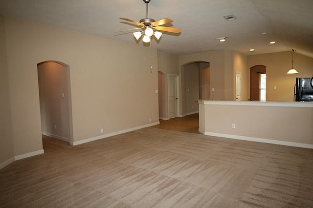 unfurnished living room featuring carpet floors, arched walkways, a ceiling fan, baseboards, and visible vents