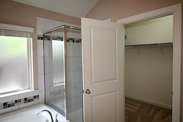 full bath with baseboards, a bath, a spacious closet, and a shower stall