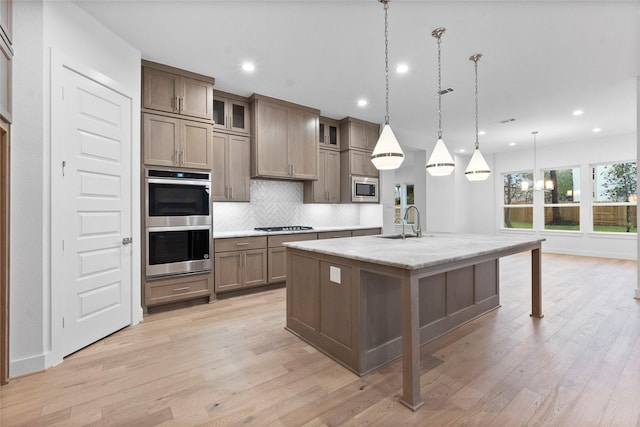 kitchen featuring decorative backsplash, recessed lighting, appliances with stainless steel finishes, and a center island with sink