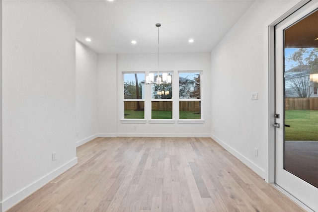 unfurnished dining area featuring light wood finished floors, recessed lighting, and a notable chandelier