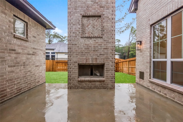 view of patio / terrace featuring an outdoor brick fireplace and a fenced backyard