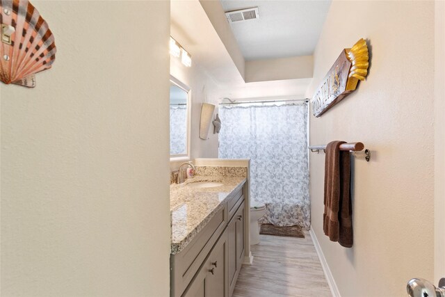full bathroom featuring wood finished floors, vanity, curtained shower, toilet, and visible vents