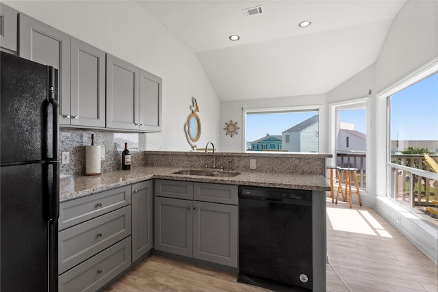 kitchen featuring lofted ceiling, a sink, black appliances, and gray cabinets