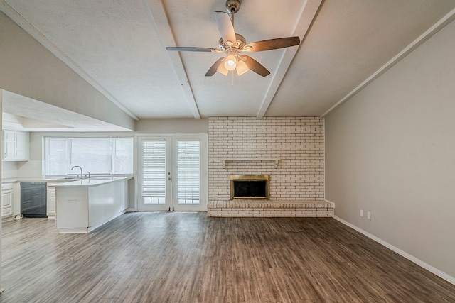 unfurnished living room with baseboards, ceiling fan, a sink, wood finished floors, and a fireplace