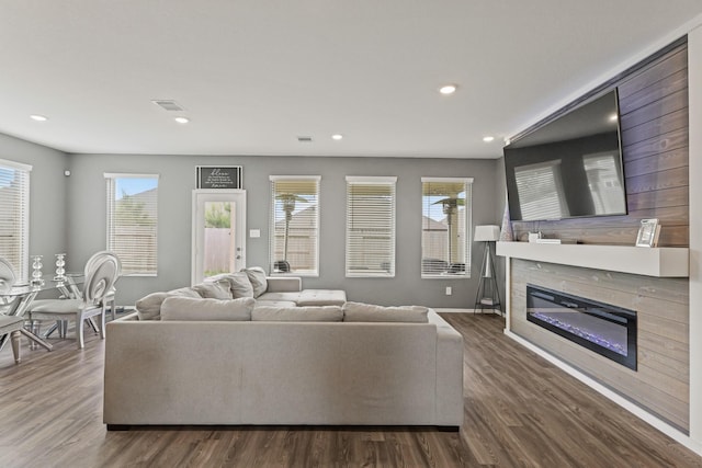living room with visible vents, baseboards, a glass covered fireplace, recessed lighting, and wood finished floors