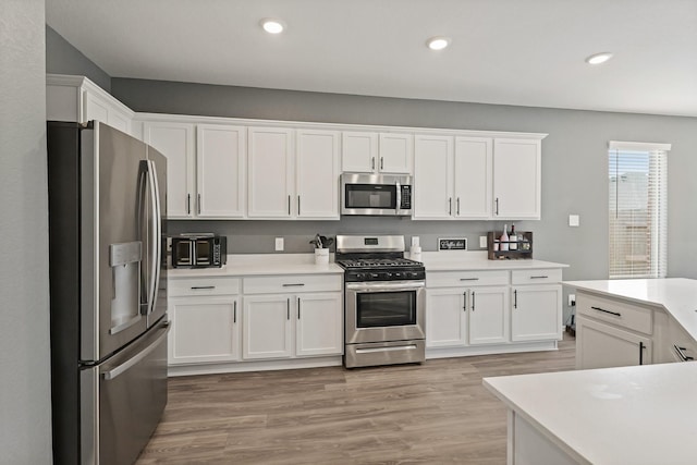 kitchen featuring recessed lighting, light wood-style flooring, light countertops, white cabinets, and appliances with stainless steel finishes